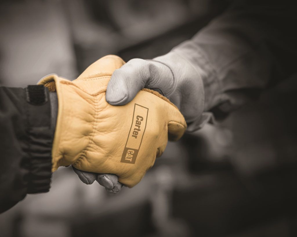 Man wearing yellow Carter Machinery work glove shaking hands with man wearing plain work glove