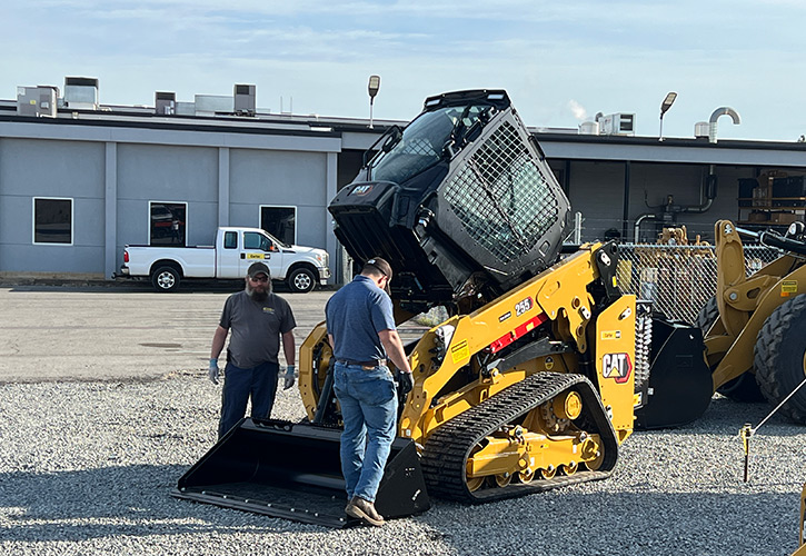 Two men looking at a Cat® 255 Compact Track Loader at a demo event